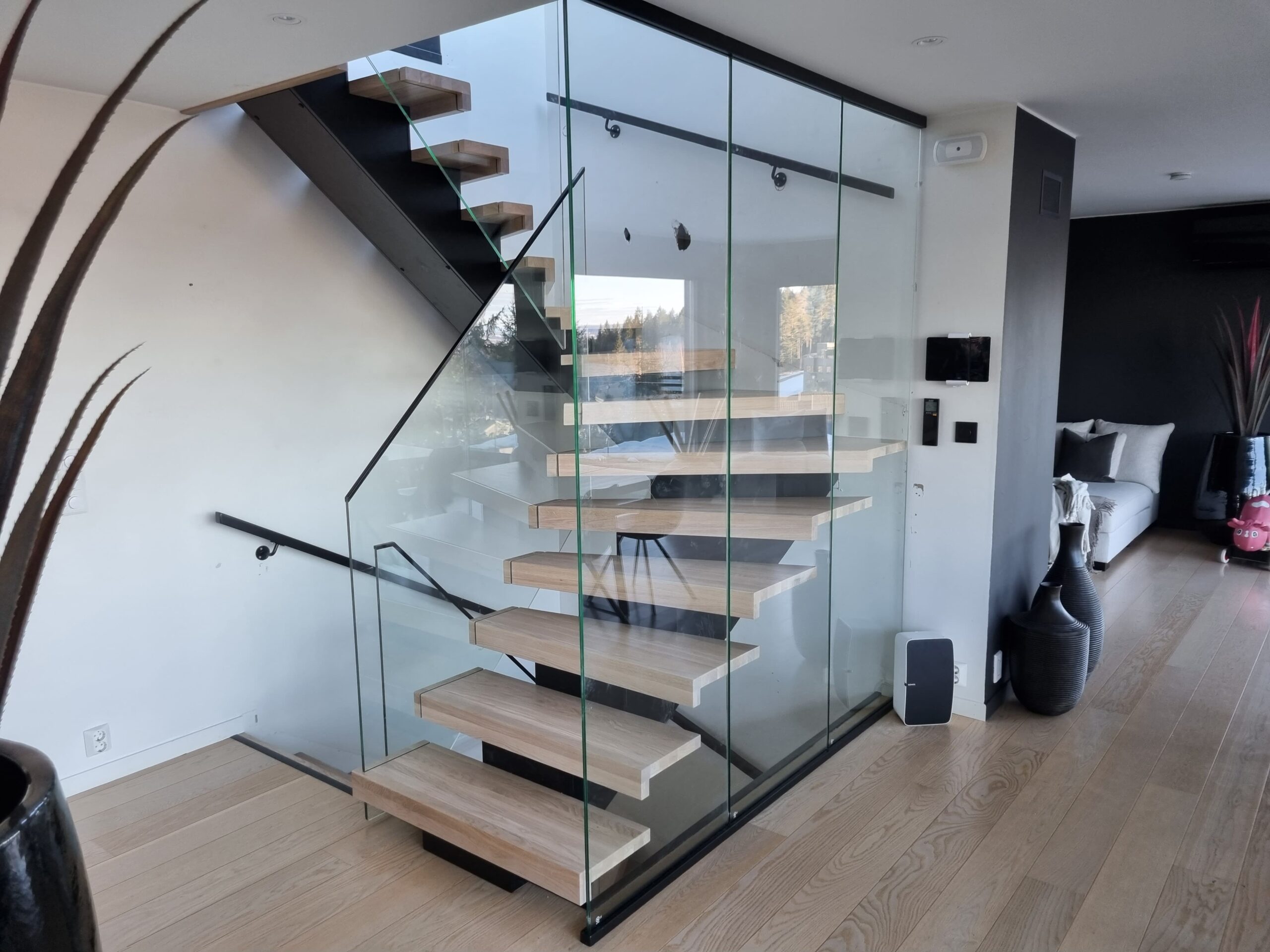 09. A staircase made of light wood with glass railing and central beam