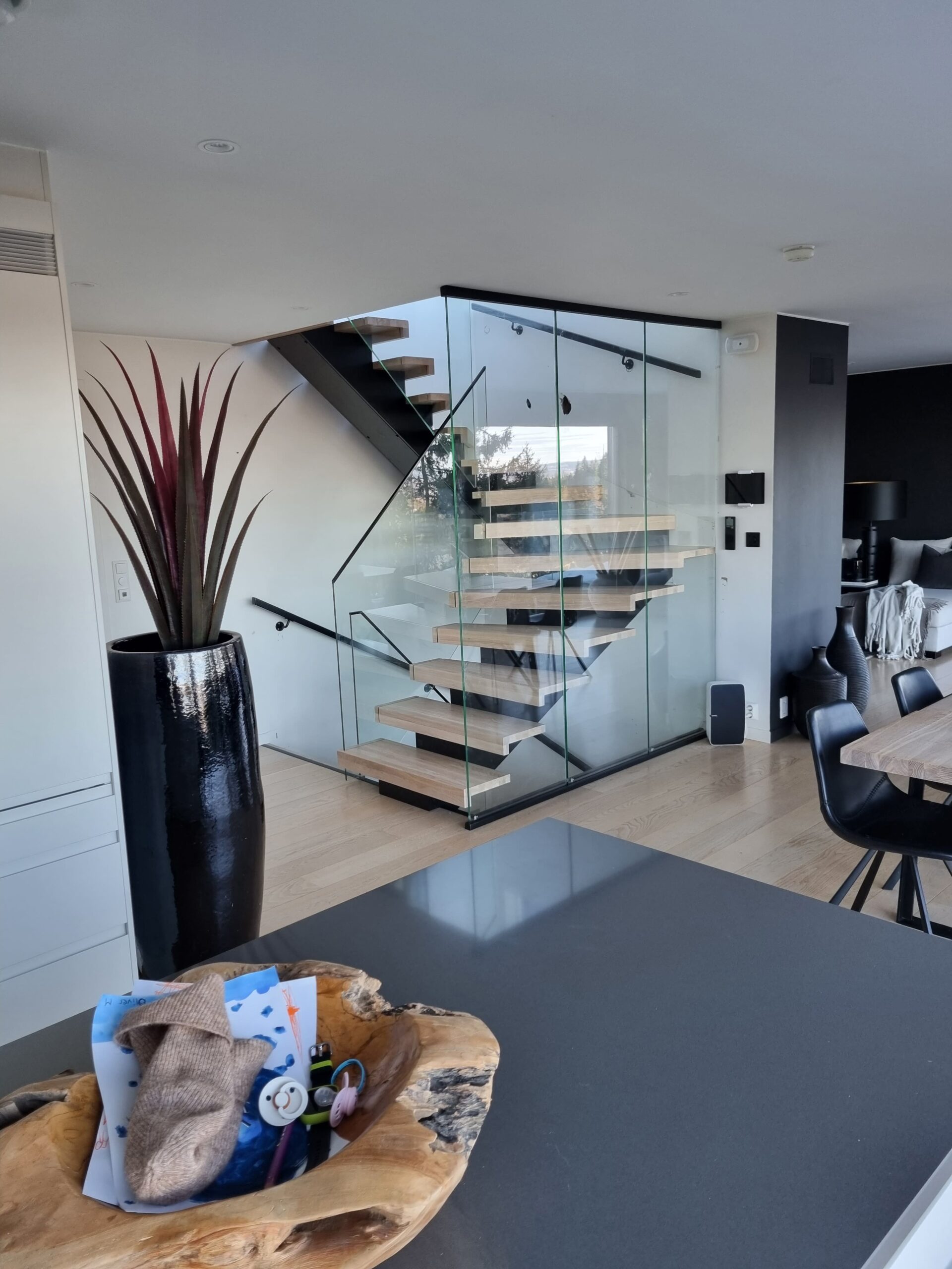 10. A staircase made of light wood with glass railing and a black central beam