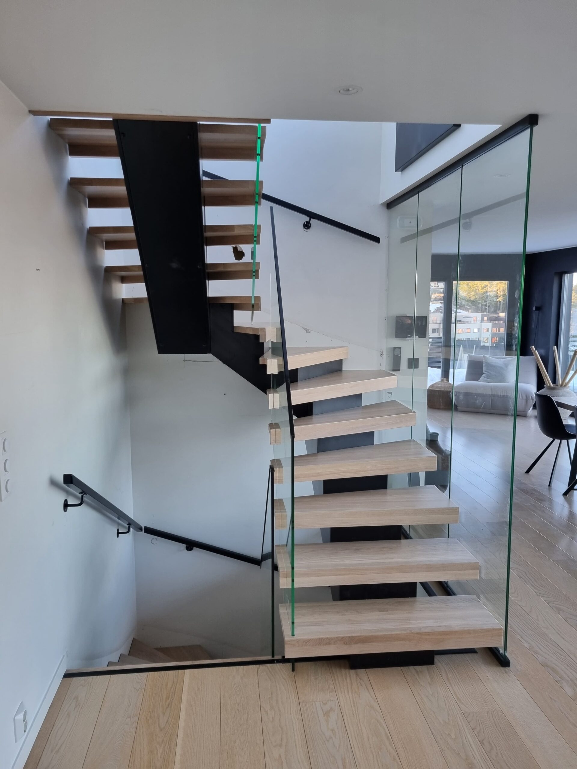 11. A staircase through two floors with glass railing and a central beam