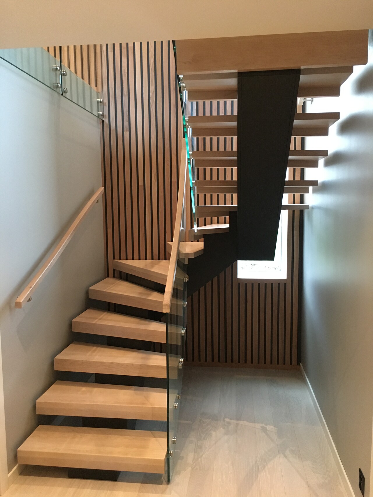 18. Wooden U-shaped staircase with a central beam and a glass railings