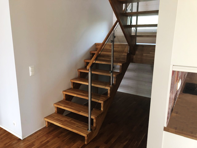 U-shaped wooden staircase with glass railing. Steps made of oak.